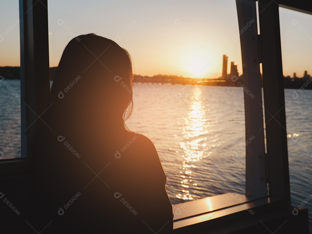 Uma mulher solitária observa o pôr do sol com vista para o mar e a cidade
