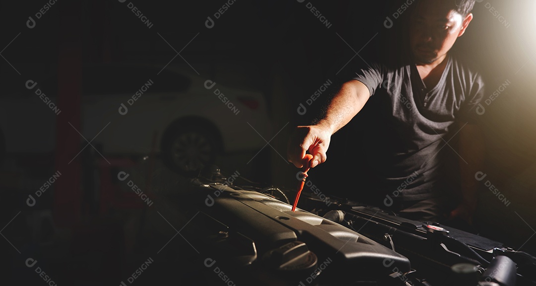 A mão do mecânico está puxando a vareta do motor do carro para verificação