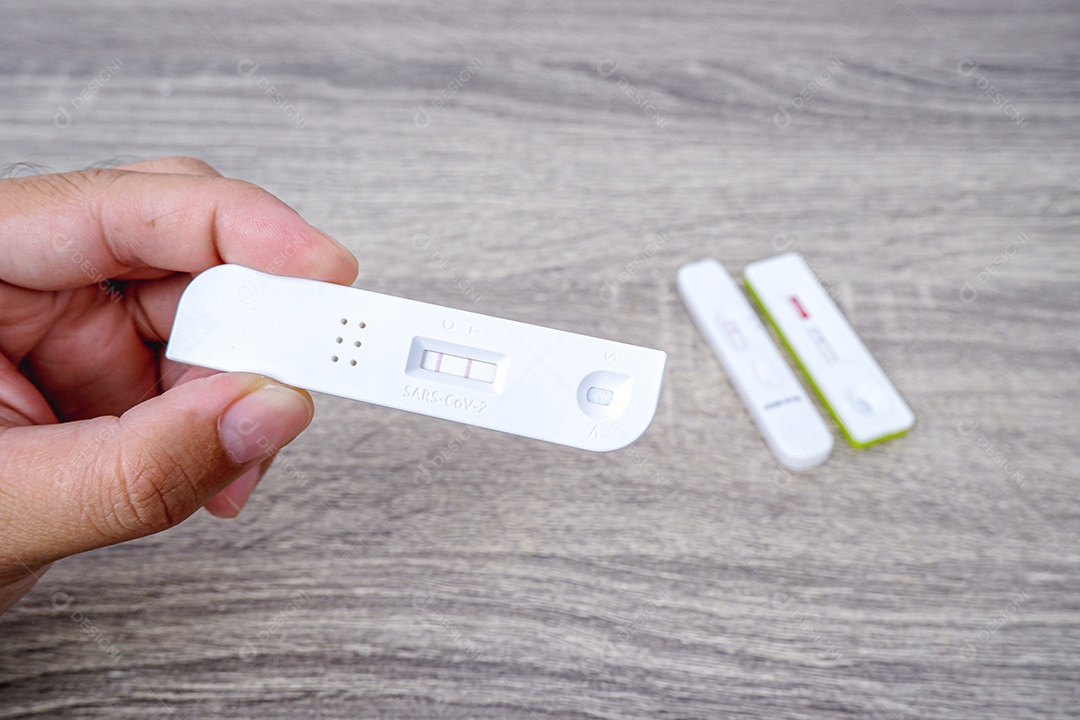 Cassete de teste Covid-19 com resultado positivo na mão