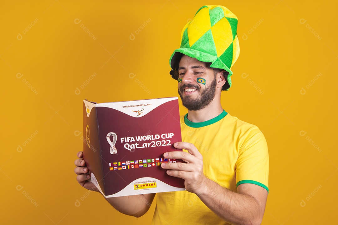 Homem brasileiro vestindo uma camiseta do Brasil e segurando um álbum da fifa