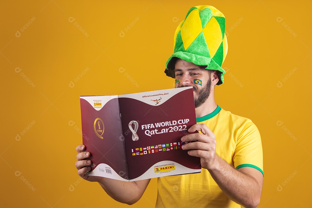 Brazilian man wearing a Brazil t-shirt and holding a fifa album