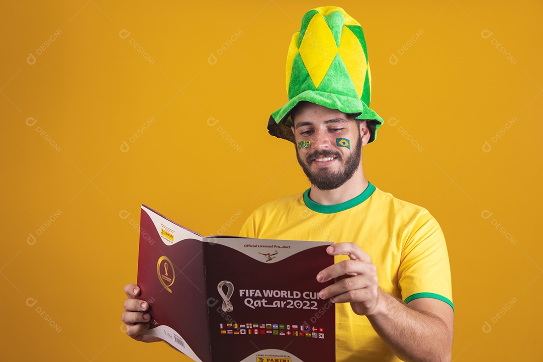 Homem brasileiro vestindo uma camiseta do Brasil e segurando um álbum da fifa