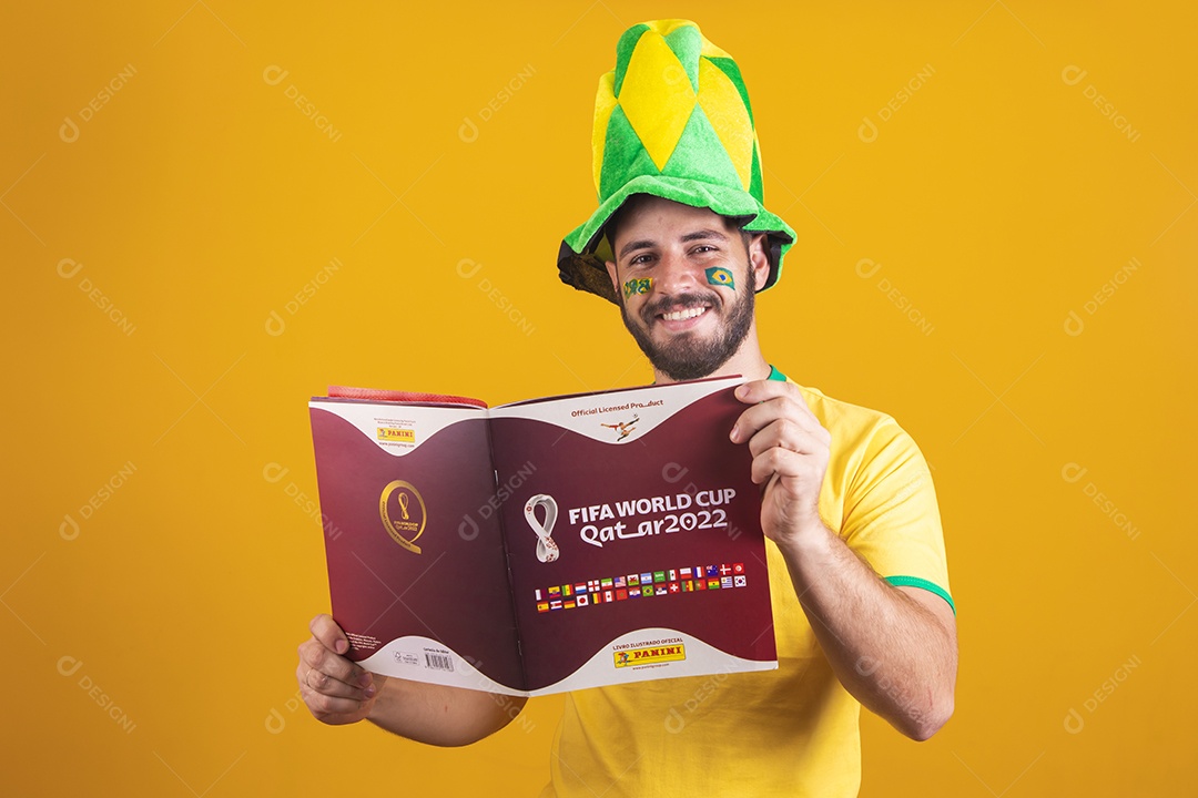 Homem brasileiro usando uma camiseta do Brasil e segurando um álbum da copa do mundo