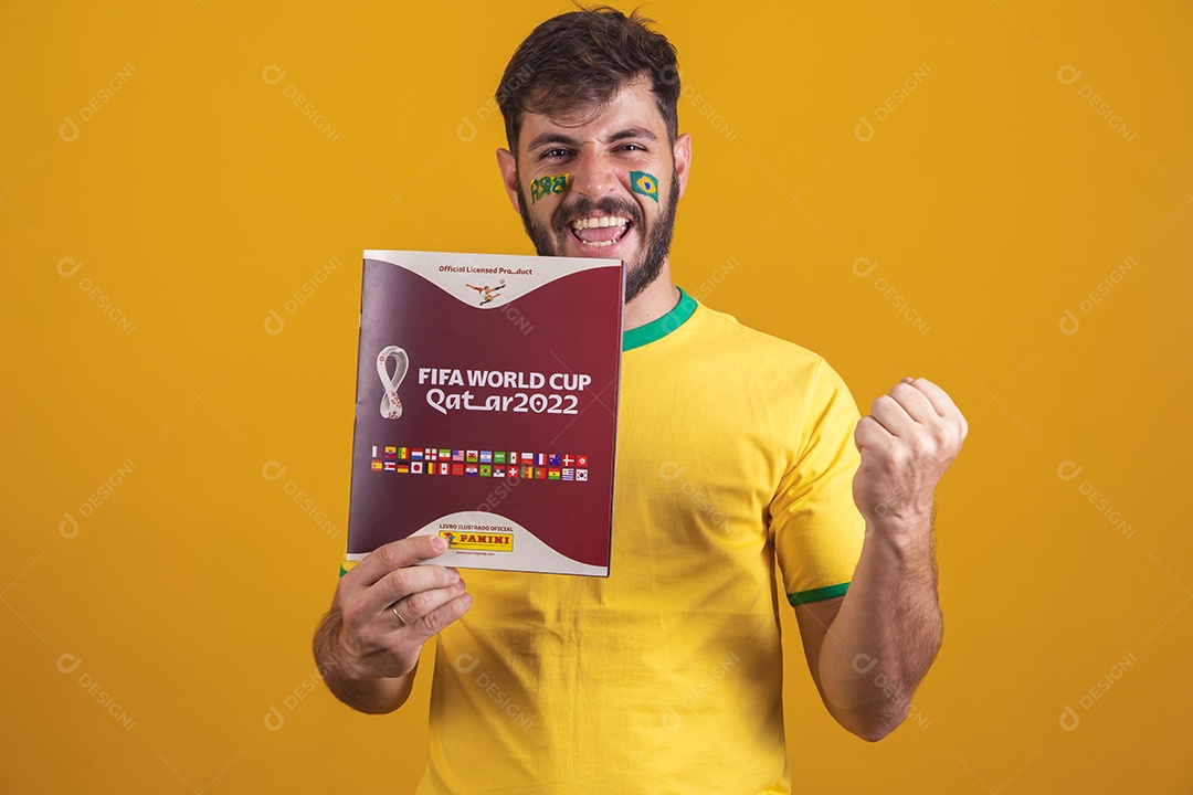 Homem brasileiro vestindo uma camiseta do Brasil e segurando um álbum da fifa