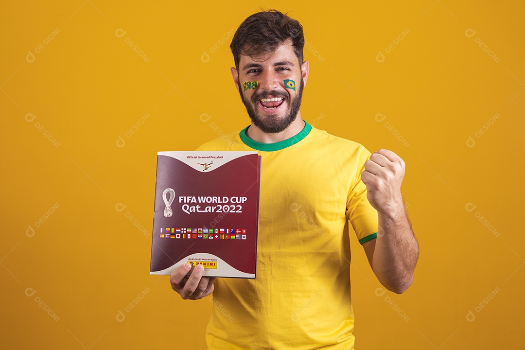 Homem brasileiro vestindo uma camiseta do Brasil e segurando um álbum da copa do mundo