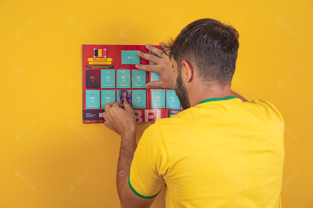 Homem colando figurinha de jogador em álbum da copa do mundo