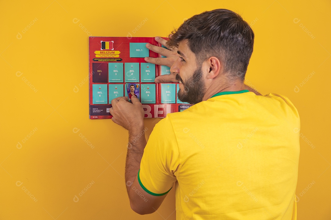 Homem colando figurinha de jogador em álbum da copa do mundo