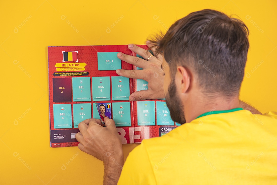 Homem colando figurinha de jogador em álbum da copa do mundo