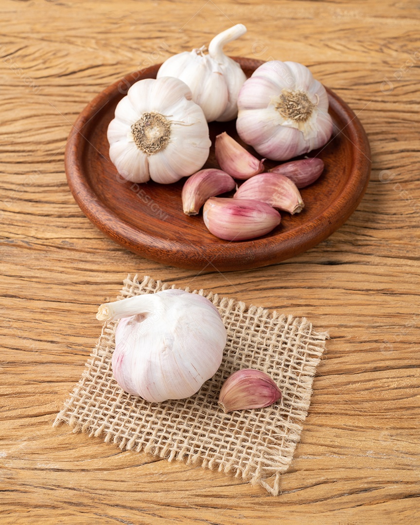 Bulbo de alho e cravo em um prato sobre a mesa de madeira.