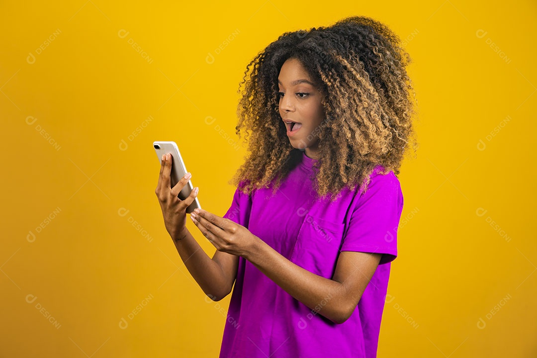 Mulher afro-brasileira usando camiseta roxa segurando um celular