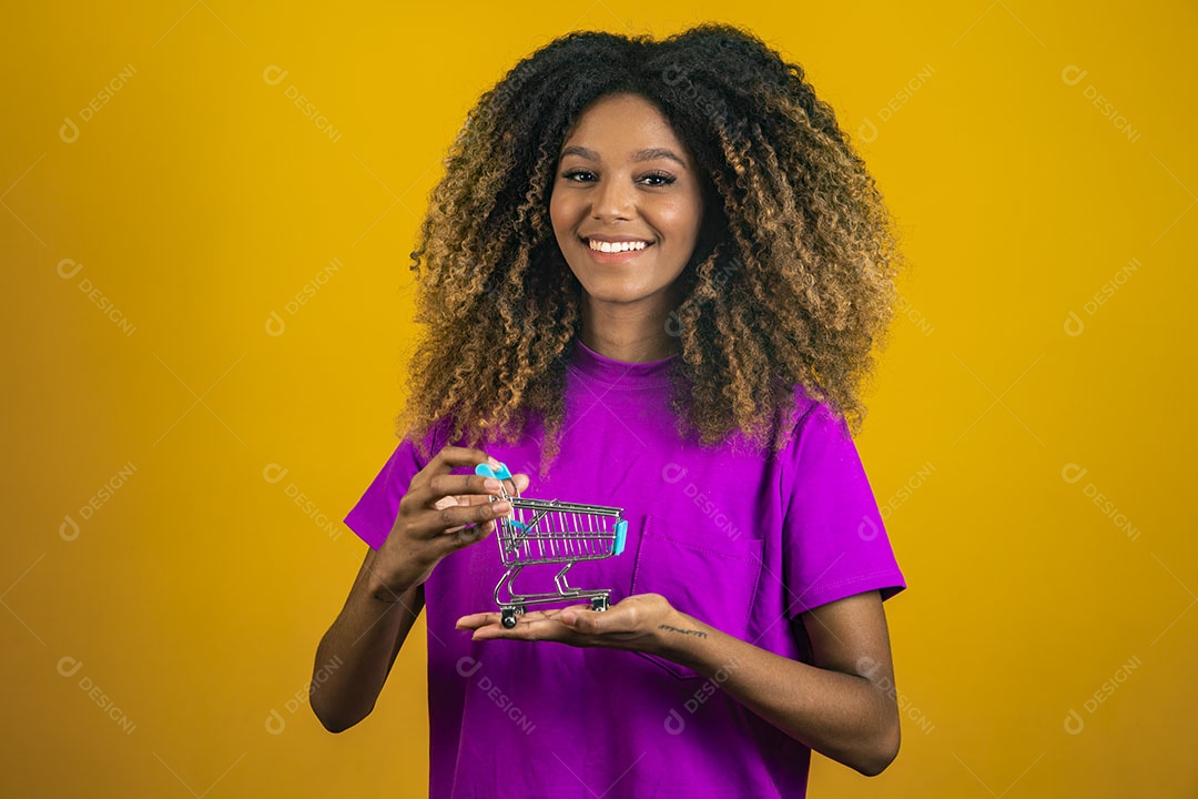 Mulher afro-brasileira usando camiseta roxa segurando um carrinho de compras