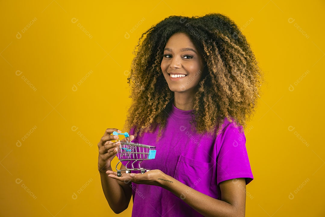 Mulher afro-brasileira usando camiseta roxa segurando um carrinho de compras