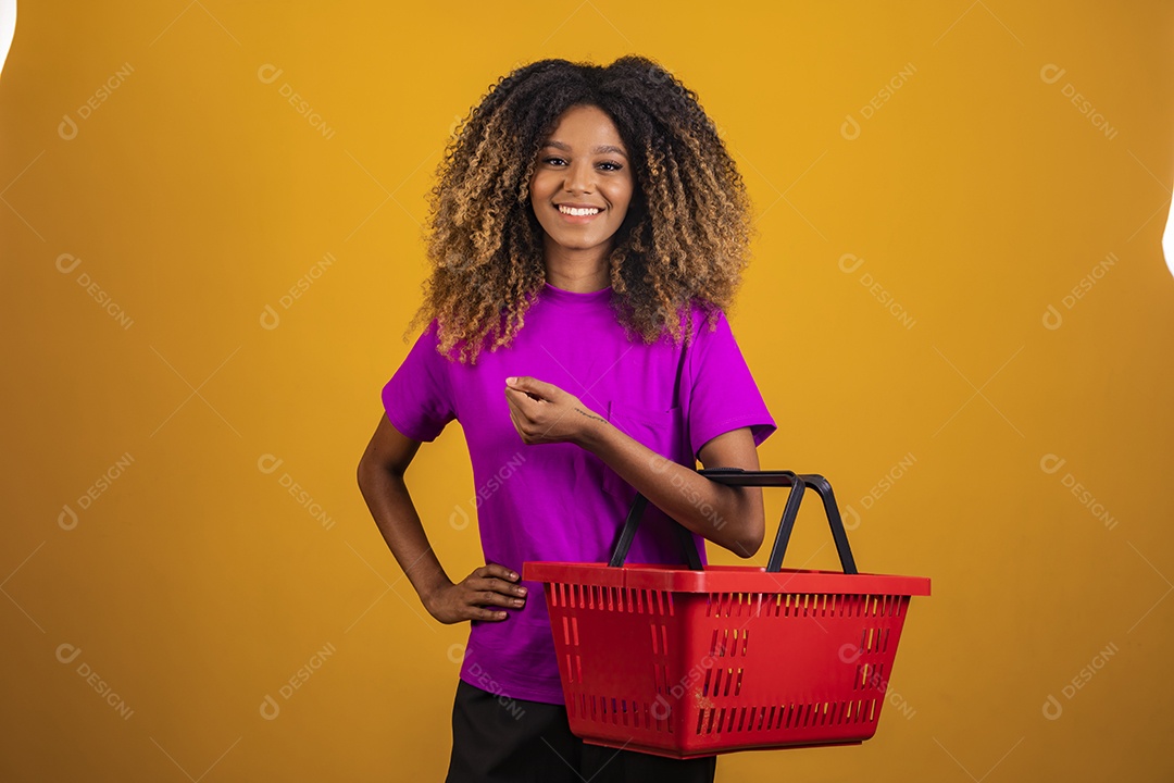 Linda mulher jovem morena cabelo afro segurando cestas mercado sobre fundo isolado amarelo