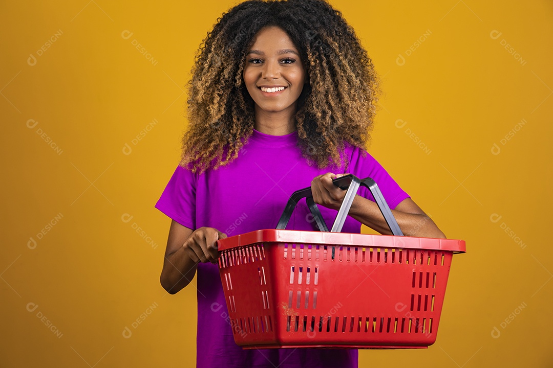 Linda mulher jovem morena cabelo afro segurando cestas mercado sobre fundo isolado amarelo