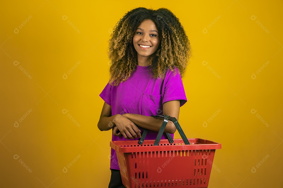 Linda mulher jovem morena cabelo afro segurando cestas mercado sobre fundo isolado amarelo