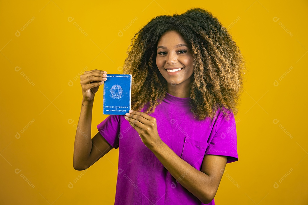 Linda mulher jovem morena cabelo afro segurando carteira de trabalho sobre fundo isolado amarelo