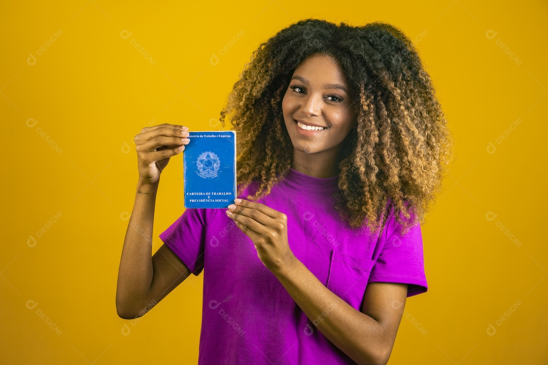 Linda mulher jovem morena cabelo afro segurando carteira de trabalho sobre fundo isolado amarelo