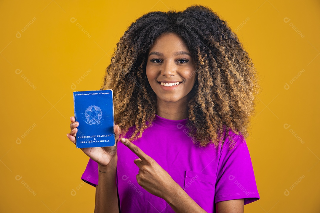 Linda mulher jovem morena cabelo afro segurando carteira de trabalho sobre fundo isolado amarelo