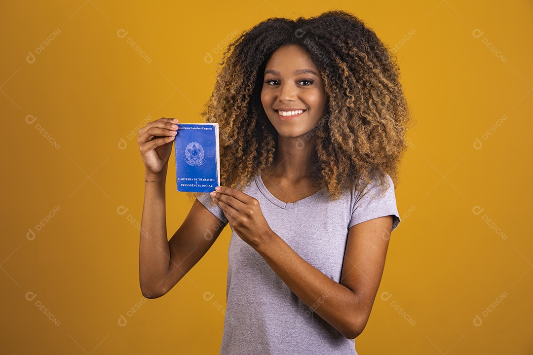 Linda mulher jovem morena cabelo afro segurando carteira de trabalho sobre fundo isolado amarelo