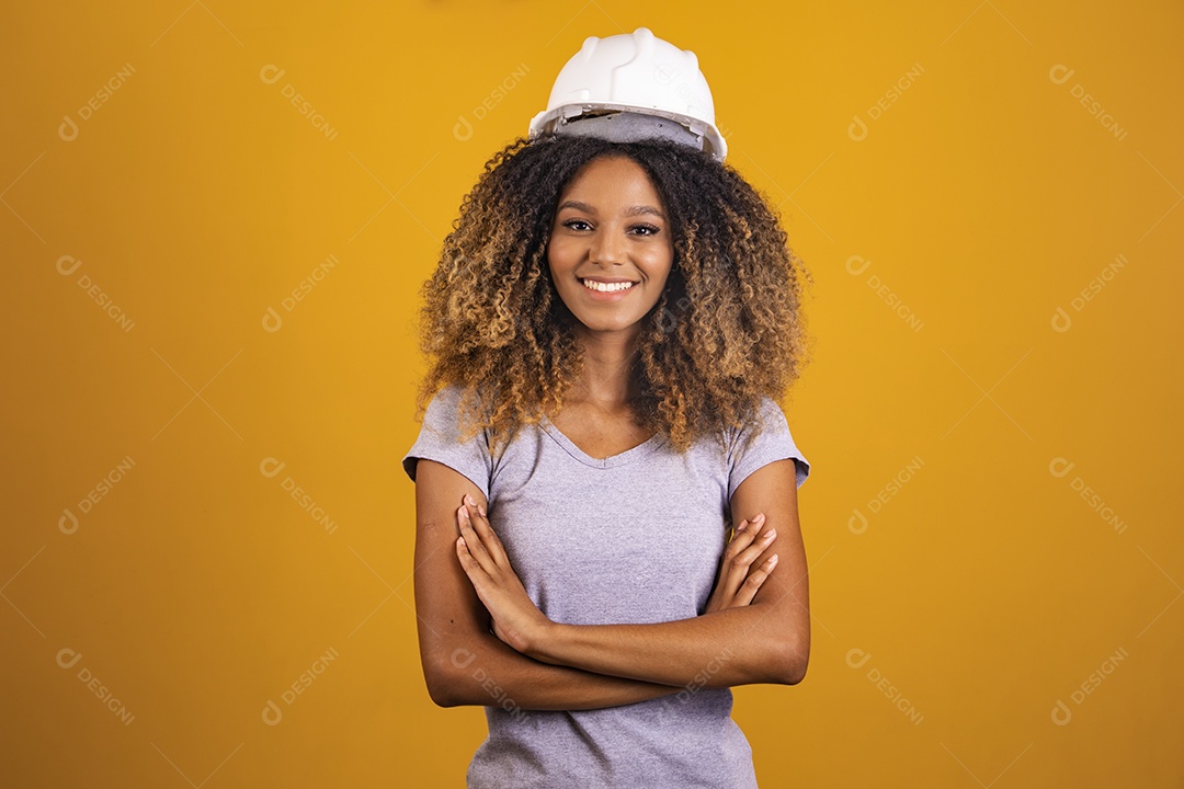 Linda mulher jovem engenheira usando capacete branco morena cabelo afro sobre fundo isolado amarelo