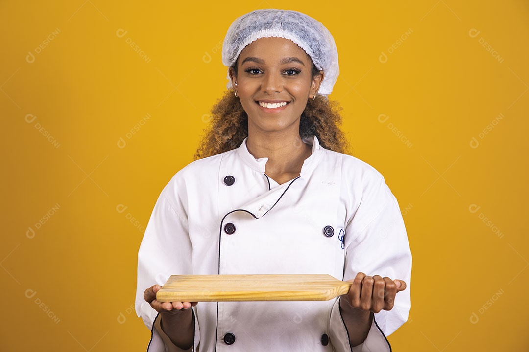 Mulher afro-brasileira usando roupa de chefe segurando um rolo de massas