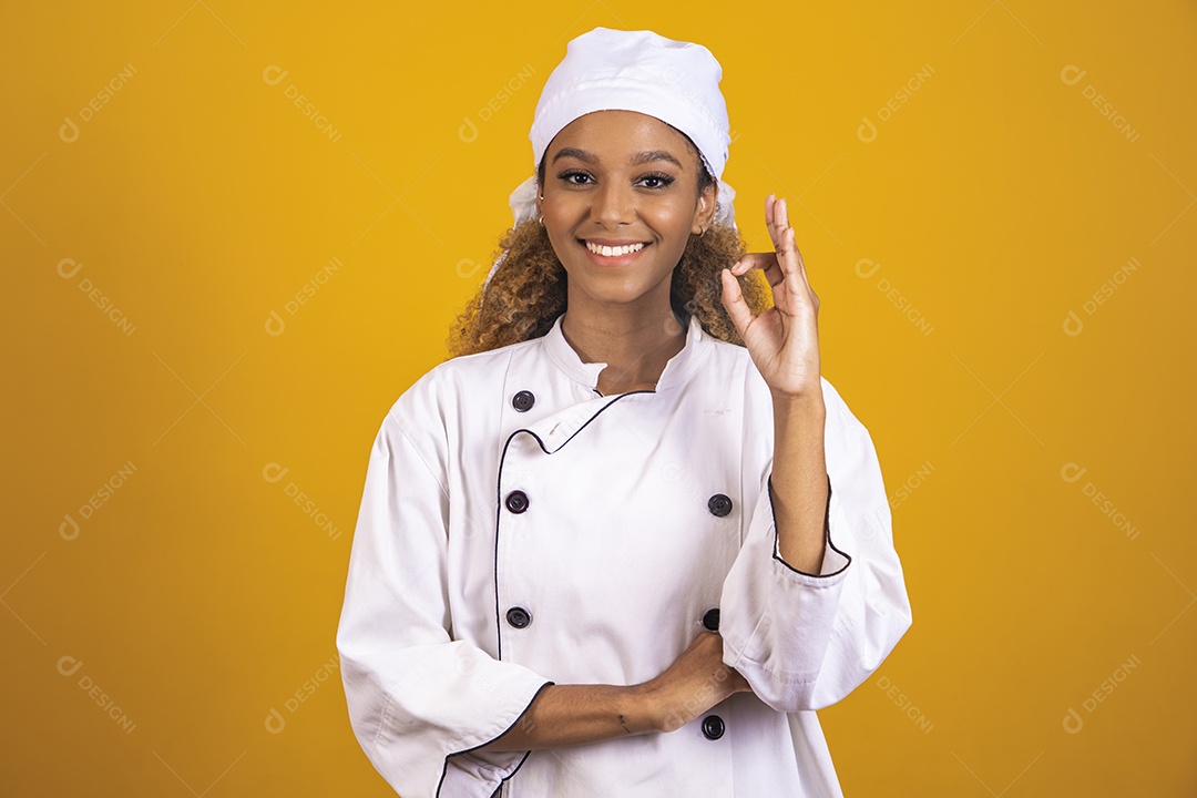 Linda mulher jovem morena cabelo afro usando avental branco sobre fundo isolado amarelo