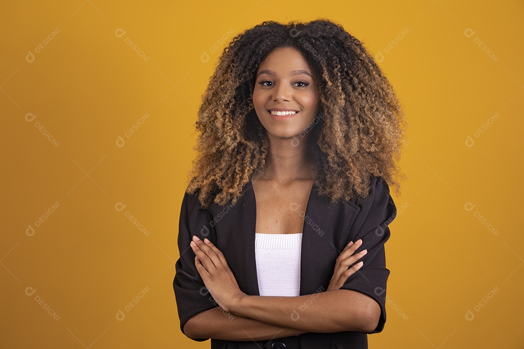 Linda mulher jovem morena cabelo afro braços cruzados sobre fundo isolado amarelo