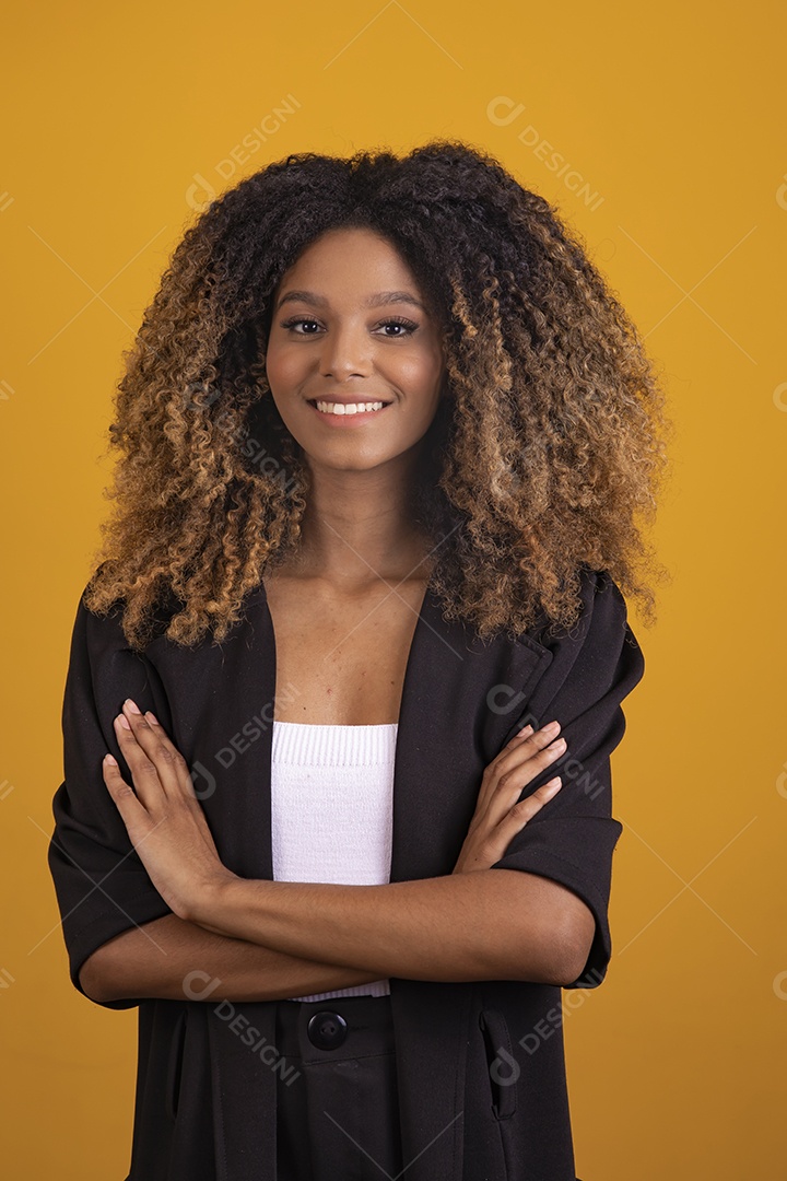 Linda mulher jovem morena cabelo afro braços cruzados sobre fundo isolado amarelo