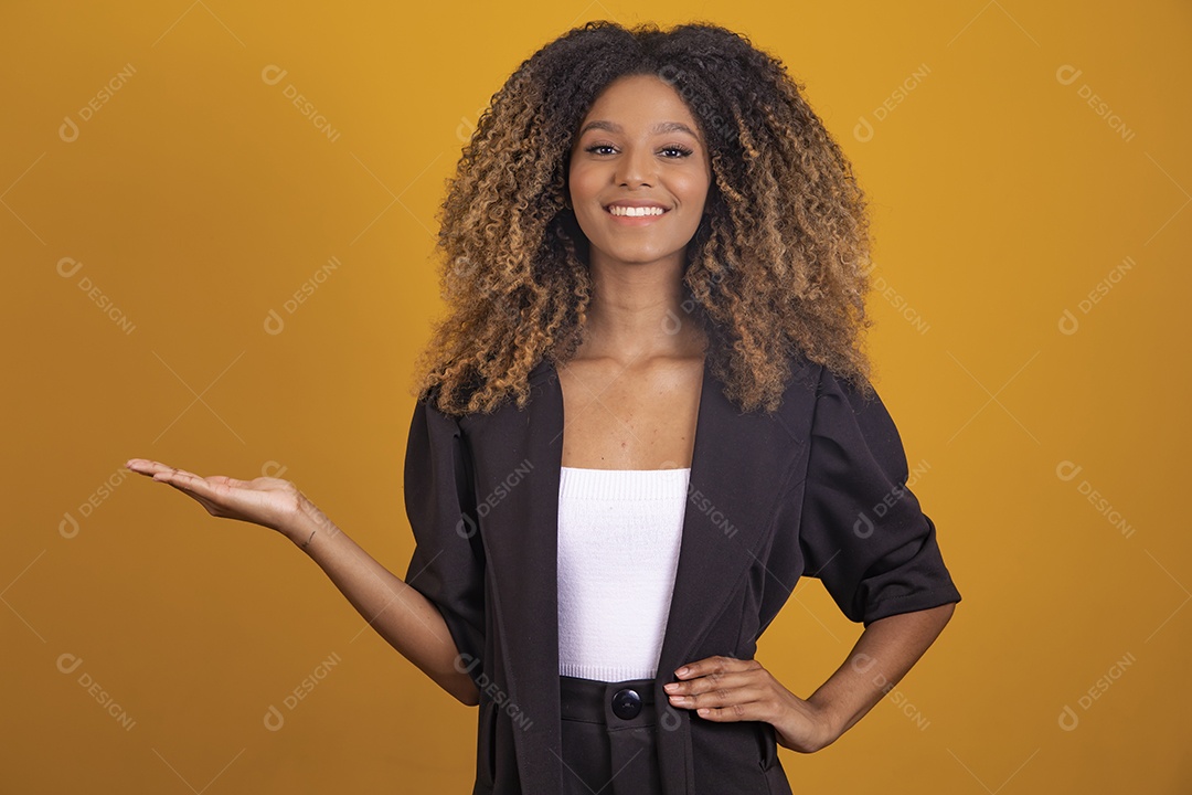 Linda mulher jovem morena cabelo afro apontando para lado sobre fundo isolado amarelo