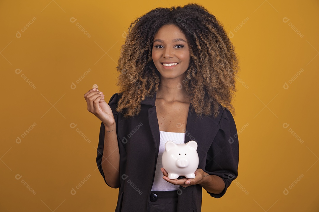 Linda mulher jovem morena cabelo afro segurando cofre sobre fundo isolado amarelo