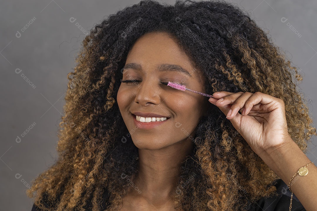 Mulher afro-brasileira vestida formalmente segurando escovinha de sobrancelhas/cílios