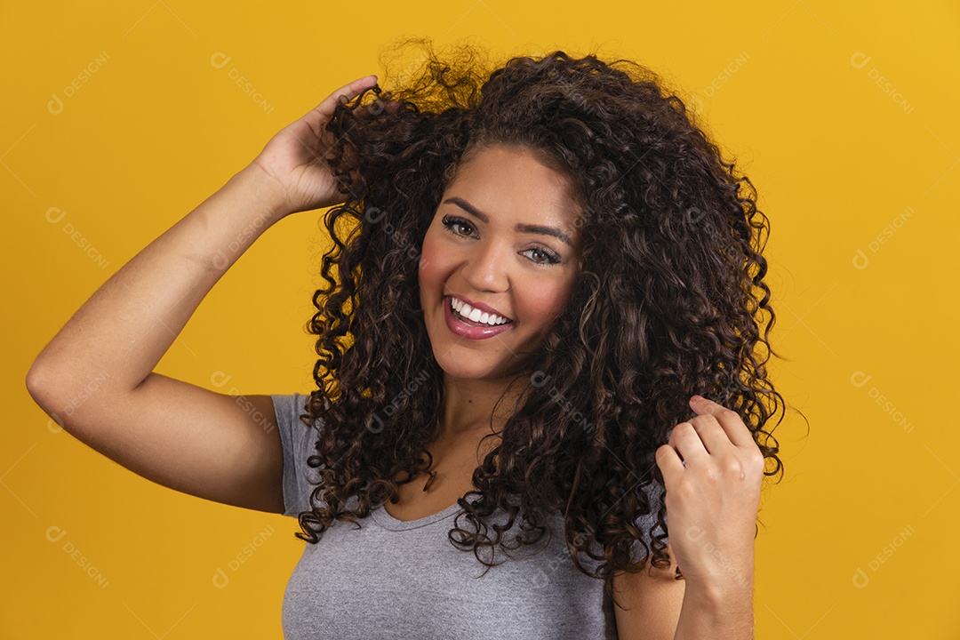 Linda mulher jovem morena cabelo cacheado sobre fundo isolado amarelo