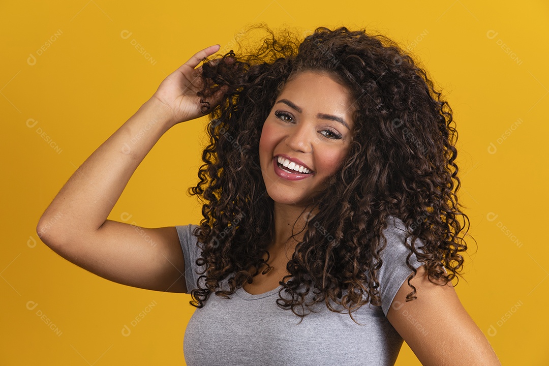Linda mulher jovem morena cabelo cacheado sobre fundo isolado amarelo
