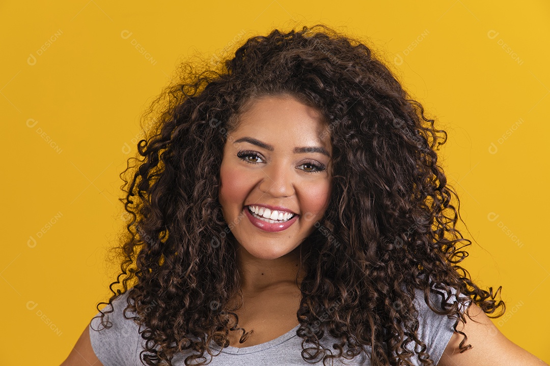 Linda mulher jovem morena cabelo cacheado sobre fundo isolado amarelo