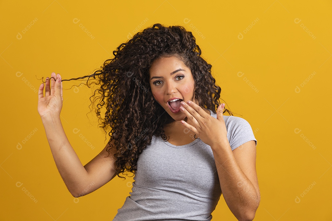 Linda mulher jovem morena cabelo cacheado sobre fundo isolado amarelo