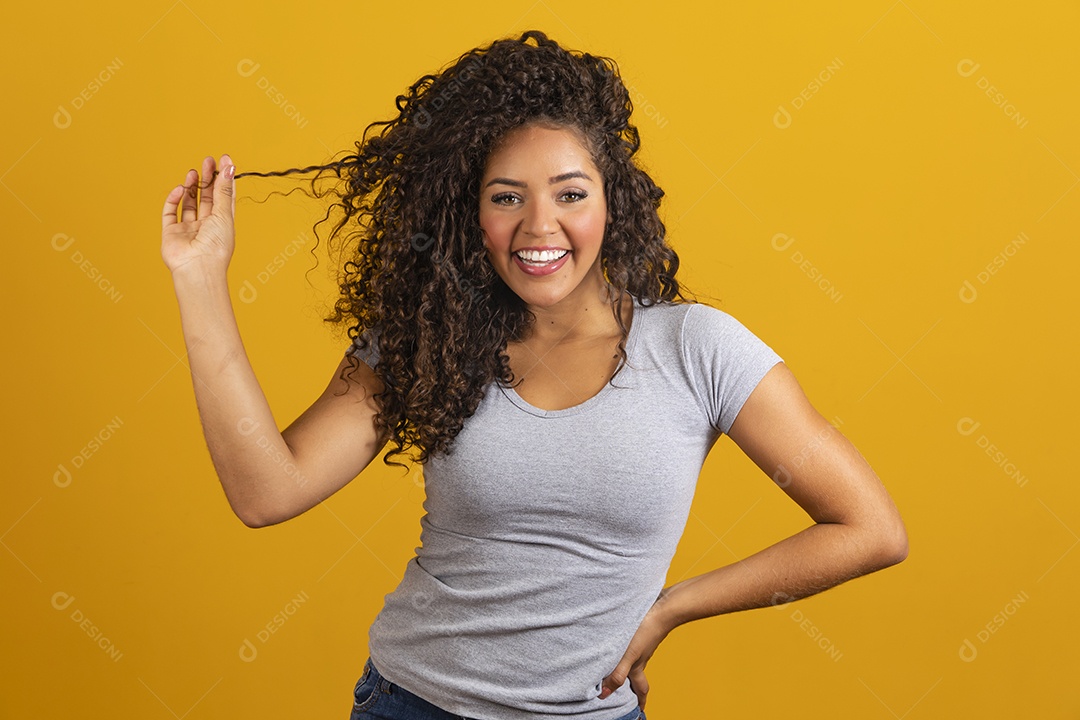 Linda mulher jovem morena cabelo cacheado sobre fundo isolado amarelo