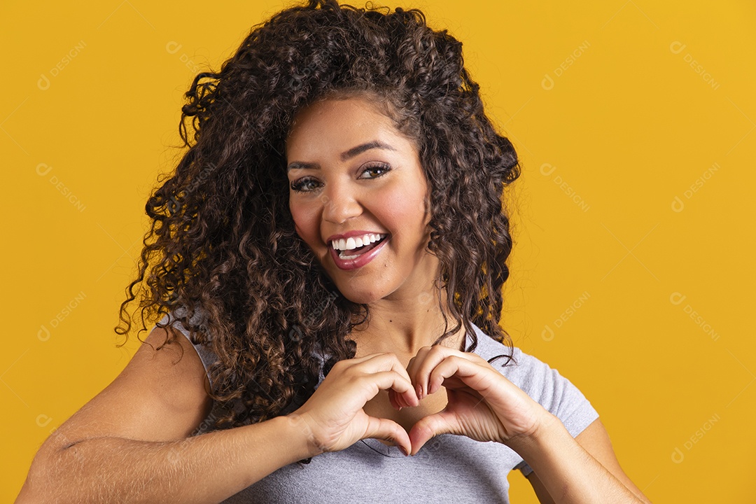 Linda mulher jovem morena cabelo cacheado sobre fundo isolado amarelo