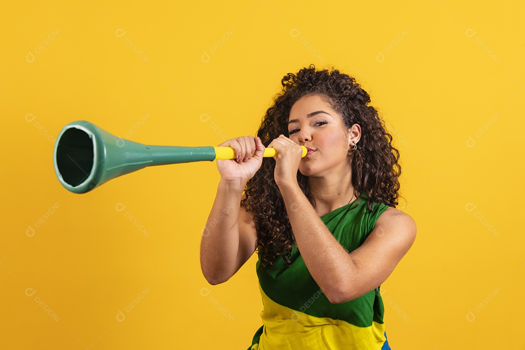 Linda mulher jovem torcedora morena brasileira cabelo cacheado sobre fundo isolado amarelo
