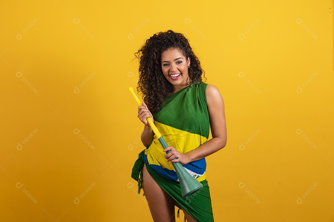 Linda mulher jovem torcedora morena brasileira cabelo cacheado sobre fundo isolado amarelo