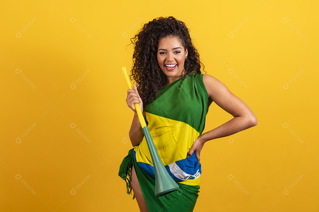 Linda mulher jovem torcedora morena brasileira cabelo cacheado sobre fundo isolado amarelo