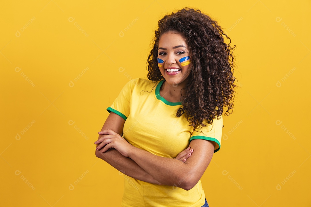 Linda mulher jovem morena segurando bandeira do brasil cabelo cacheado sobre fundo isolado amarelo