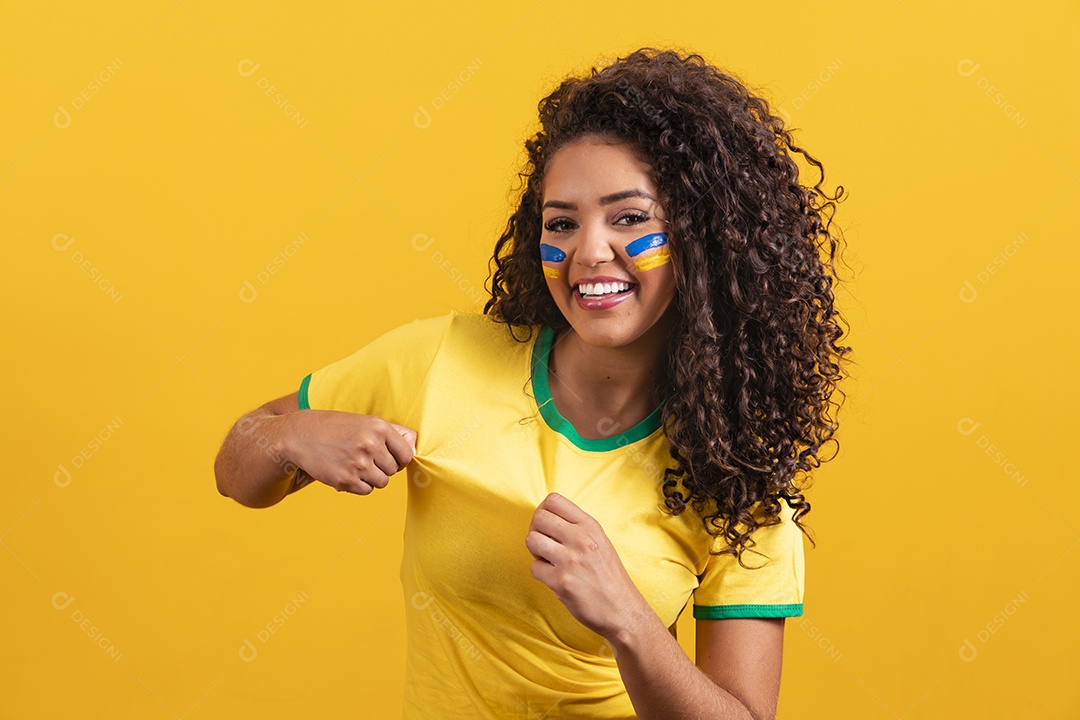 Linda mulher jovem morena segurando bandeira do brasil cabelo cacheado sobre fundo isolado amarelo