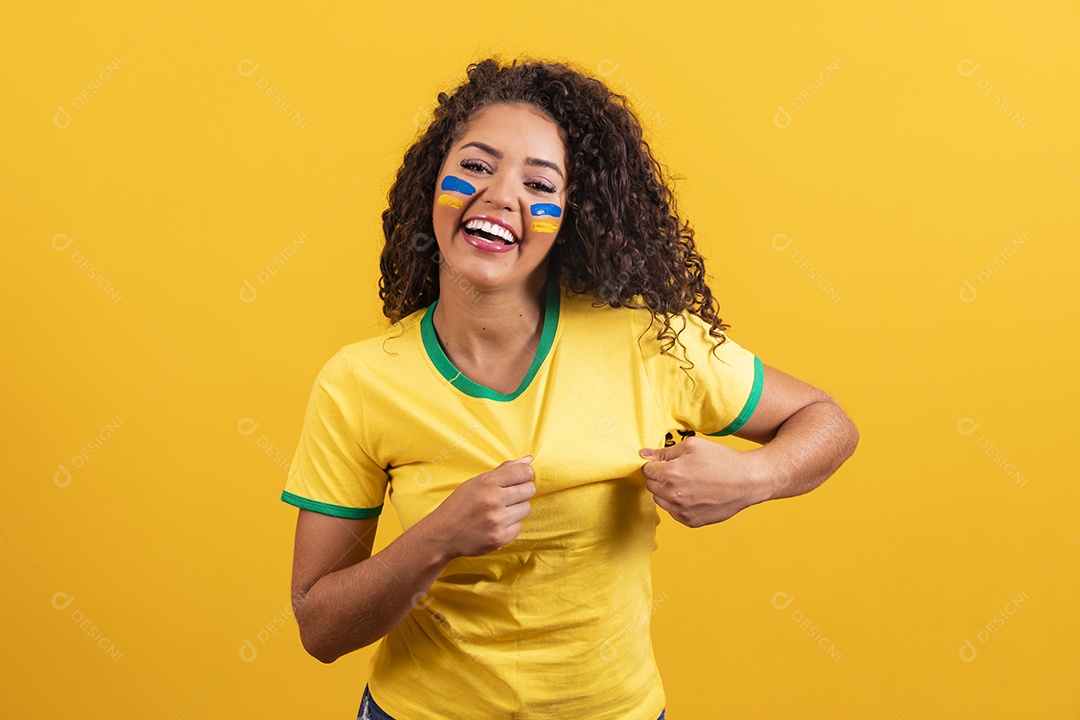 Linda mulher jovem morena segurando bandeira do brasil cabelo cacheado sobre fundo isolado amarelo