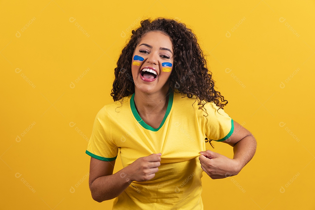 Linda mulher jovem morena segurando bandeira do brasil cabelo cacheado sobre fundo isolado amarelo