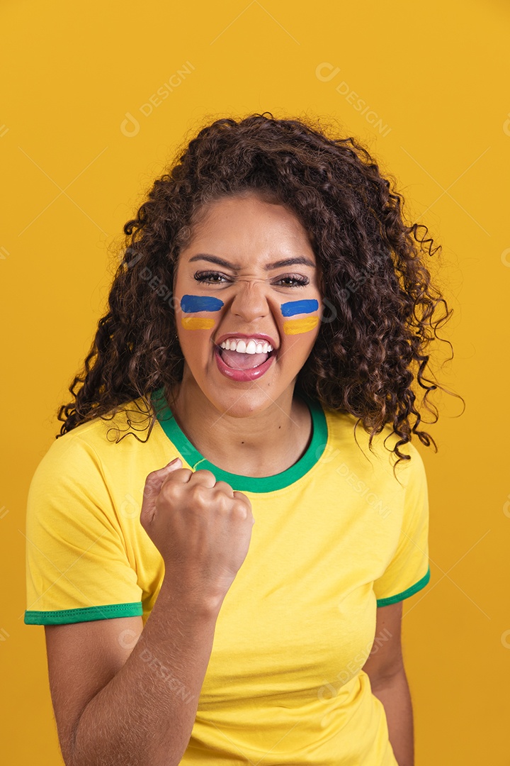 Linda mulher jovem morena segurando bandeira do brasil cabelo cacheado sobre fundo isolado amarelo