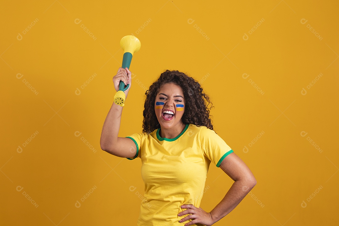 Linda mulher jovem morena segurando bandeira do brasil cabelo cacheado sobre fundo isolado amarelo