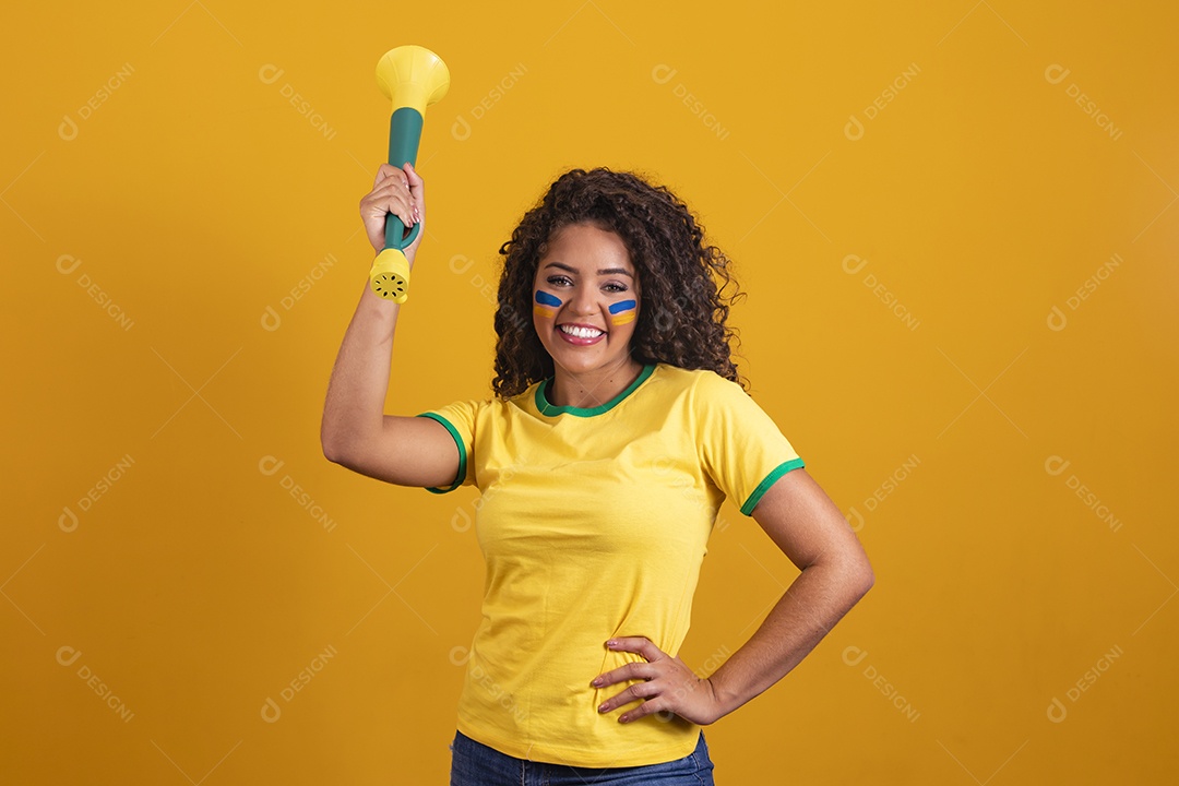 Linda mulher jovem morena segurando bandeira do brasil cabelo cacheado sobre fundo isolado amarelo