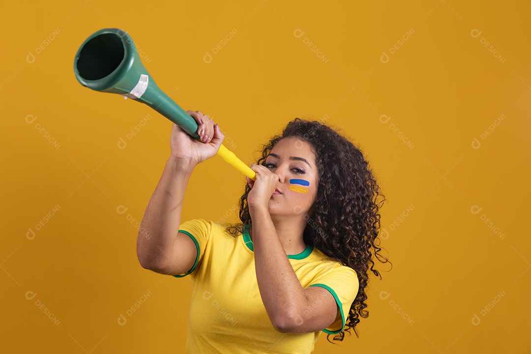 Linda mulher jovem morena segurando bandeira do brasil cabelo cacheado sobre fundo isolado amarelo