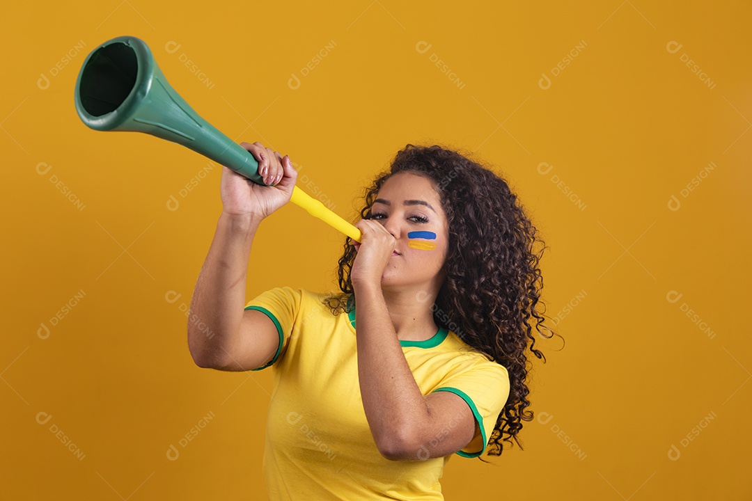 Linda mulher jovem morena segurando bandeira do brasil cabelo cacheado sobre fundo isolado amarelo