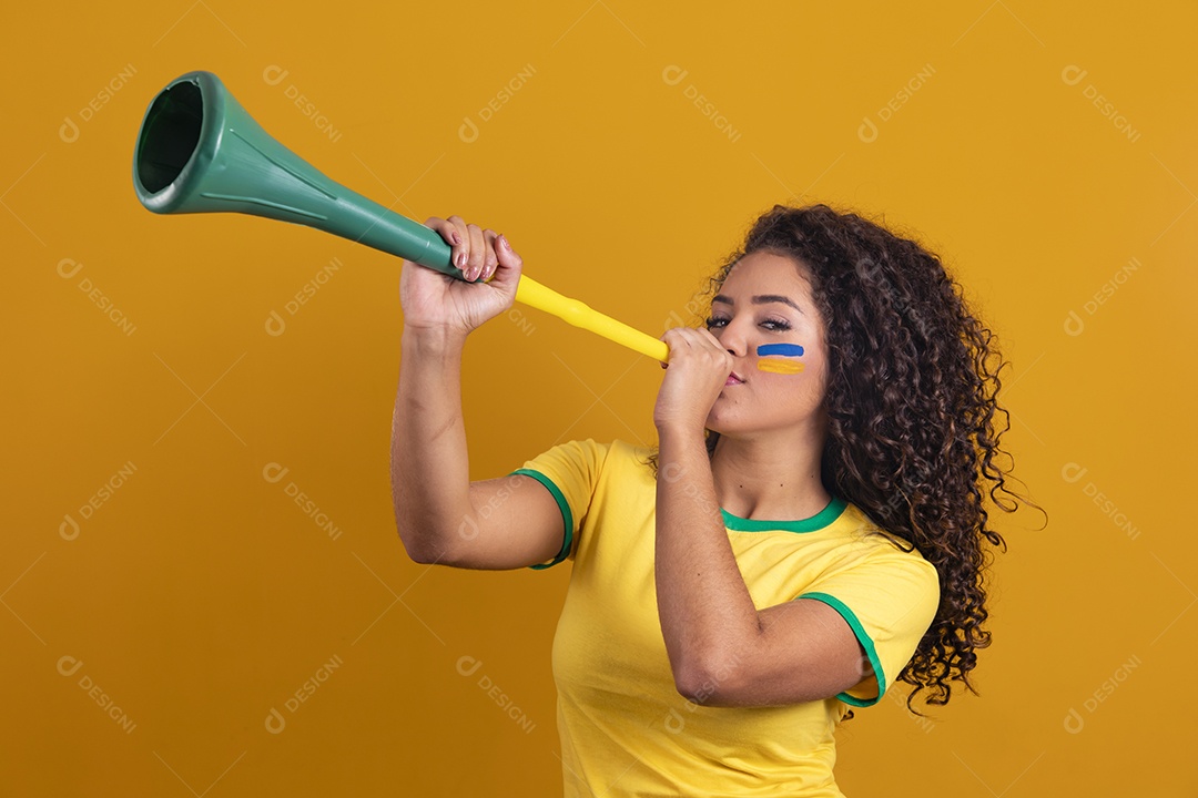 Linda mulher jovem morena segurando bandeira do brasil cabelo cacheado sobre fundo isolado amarelo